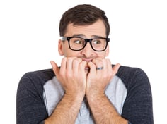 Closeup portrait of nervous, stressed young nerdy guy man with eyeglasses biting fingernails looking anxiously craving something isolated on white background. Negative emotion expression feeling-1